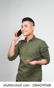 Portrait Of A Cheerful Young Asian Man On Call Against Grey Background