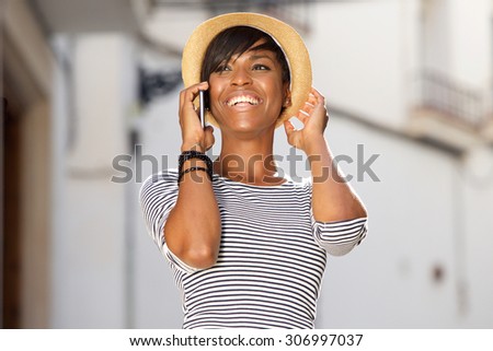 Portrait of a cheerful young black woman talking on mobile phone