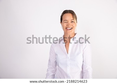 Portrait of cheerful young businesswoman sticking out tongue. Caucasian woman wearing white shirt looking at camera and winking. Successful businesswoman concept