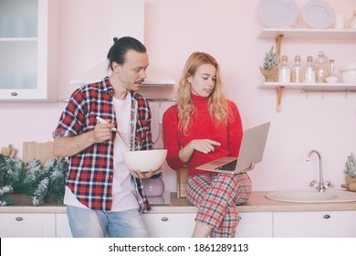 Portrait Of A Cheerful Young Couple Cooking Christmas Meal Together According To A Recipe On A Tablet Computer