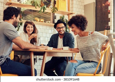 Portrait of cheerful young friends having fun while talking in a cafe. Group of young people meeting in a cafe. - Powered by Shutterstock