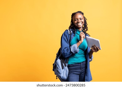 Portrait of cheerful young girl smiling, reading and writing for school exam on notepad, studio background. Joyous student holding exercise notebook with research done for university courses - Powered by Shutterstock