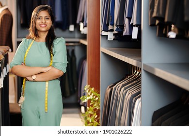 Portrait of cheerful young Indian shop assistant standing in store with arms folded and looking at camera - Powered by Shutterstock