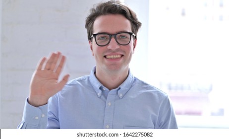 Portrait Of Cheerful Young Man Waving At The Camera