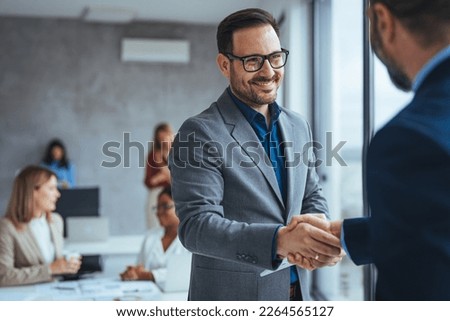 Portrait of cheerful young manager handshake with new employee. Business partnership meeting in office. Close up of handshake in the office. Mature businessman shake hands with a younger colleague