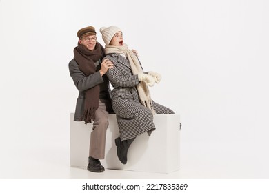 Portrait Of Cheerful Young People, Man And Woman In Winter Clothes Having Fun Together, Sledding Over White Background. Concept Of Retro Fashion, Style, Friendship, Creativity, Youth, Emotions, Ad