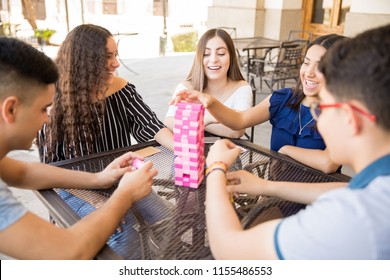 Portrait Of Cheerful Young People Sitting At Cafe Table And Playing Board Games
