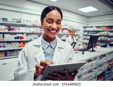 Portrait of cheerful young woman browsing digital tablet working in pharmacy with colleague in background - Powered by Shutterstock