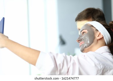 Portrait of cheerful young woman and man posing for selfie. Smiling couple applying hydrating facial masks. Spa day, wellness, skincare and healthcare concept - Powered by Shutterstock