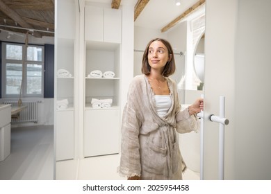 Portrait Of A Cheerful Young Woman Opening The Bathroom Door At Modern Studio Apartment. Person Feeling Comfortable And Cozy At Home