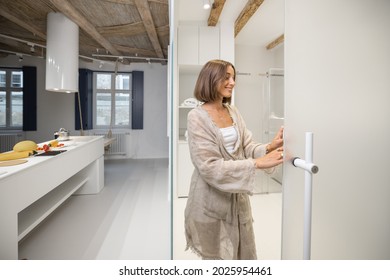 Portrait Of A Cheerful Young Woman Opening The Bathroom Door At Modern Studio Apartment. Person Feeling Comfortable And Cozy At Home