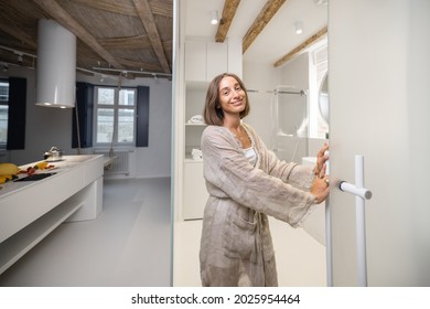 Portrait Of A Cheerful Young Woman Opening The Bathroom Door At Modern Studio Apartment. Person Feeling Comfortable And Cozy At Home