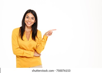 Portrait of a cheerful young woman pointing finger away at copy space isolated over white background