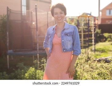 Portrait cheerful young woman wearing stylish dress in patio. Happy smiling girl making having fun outdoor. Happy beautiful woman enjoying summer