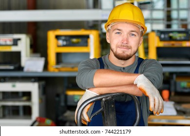 Portrait of cheerful young worker wearing hardhat posing looking at camera and smiling enjoying work at modern factory