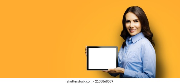 Portrait Of Cheerfully Smiling Brunette Businesswoman Showing Mock Up Blank Tablet Pc, Ipad Touchpad, With Copy Space Area For Text, Over Yellow Color Background. Confident Business Woman At Studio