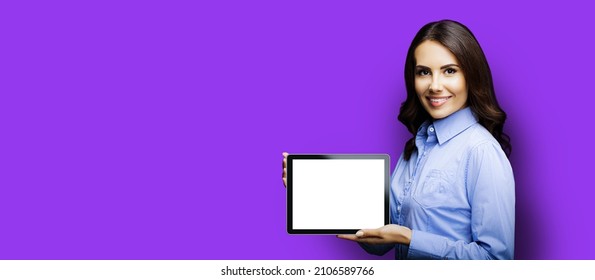 Portrait Of Cheerfully Smiling Brunette Businesswoman Showing Mock Up Blank Tablet Pc, Ipad Touchpad, With Copy Space Area For Text, Over Violet Purple Background. Confident Young Business Woman