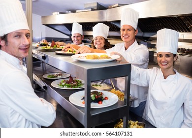 Portrait of chef team smiling in commercial kitchen - Powered by Shutterstock