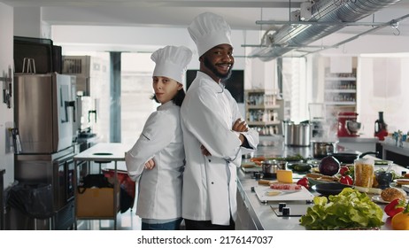 Portrait Of Chefs Doing Teamwork To Cook Food Recipe In Restaurant Kitchen, Sitting With Arms Crossed. Diverse Team Of Cooks Preparing To Make Culinary Dish And Gourmet Meal With Fresh Ingredients.