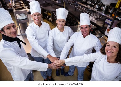 Portrait Of Chefs Team Putting Hands Together And Cheering In A Commercial Kitchen