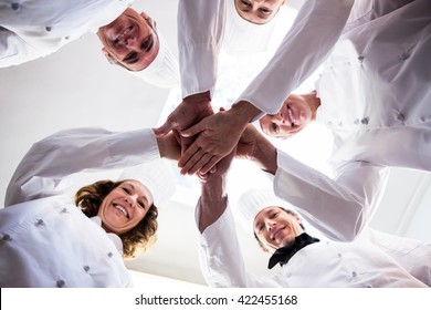 Portrait of chefs team putting hands together and cheering in a commercial kitchen - Powered by Shutterstock