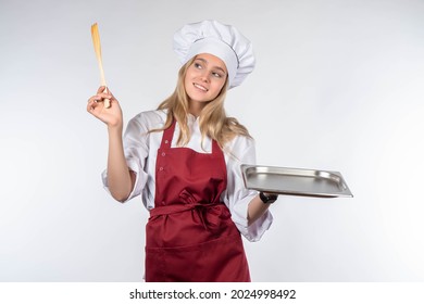 Portrait Of Chief In Working Uniform. Empty Tray In Hands Of Chef. Cook In Red Apron. Girl Cook Smiles. Blonde-haired Woman Is Cook. Restaurant Chef On White Background. Place For Dish On Tray