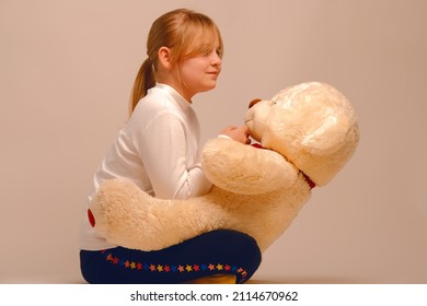 Portrait of a child with a bear cub in her arms. A young girl plays with a toy bear at home