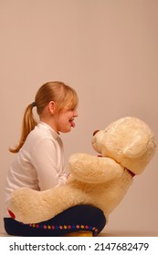 Portrait of a child with a bear cub in her arms. A young girl plays with a toy bear at home
