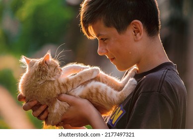 Portrait child boy outdoors  warm sunny summer day. smiling boy inature looking camera Happy blond boy  black t shirt summer vacation  playing red cat Beautiful teenager