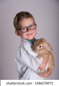 Portrait Of Child Boy With Rabbit In Hands. Funny Child In Glasses With Bunny Pet. 