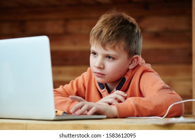 Portrait Of A Child Boy With A Smart Focused Face Doing Homework At A Laptop Computer, Distance Studying At Online School