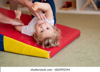 Portrait of a child with cerebral palsy on physiotherapy in a children therapy center. Boy with disability has therapy by doing exercises. Special needs kid has therapy with physiotherapist.