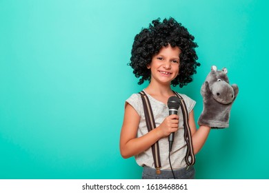 Portrait Of Child Comedian Performing With A Puppet, Isolated On Mint Colored Background