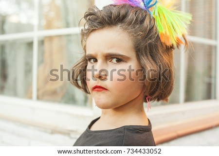 Portrait child dressed as a rocker with star earings and rainbow hair accesory.