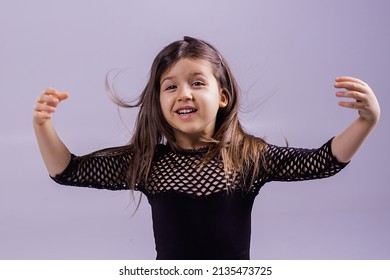 Portrait Of A Child Of A Girl Of Five Years Of A Shocked Crazy Smiling Girl Raising Her Arms And Hair. Close-up Of A Baby Girl On A Pink Background