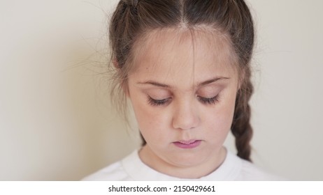 Portrait Child Girl Looking At The Camera. Happy Family Kid Dream Concept. Baby Eyes Down Then Look At The Camera And Smiles. Portrait Girl Kid Indoors Close-up. Smile No Milk Teeth Funny Fell Out