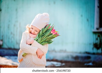 Portrait Of Child Girl With Tulips Having Fun On The Walk In Early Spring