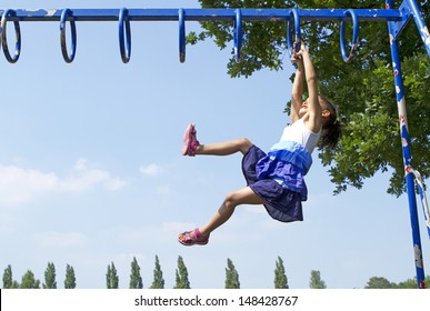 Portrait Of A Child Playing And Swinging Along On Monkey Bars Outdoors