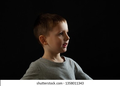 Portrait Of A Child In Profile On A Black Background. Boy Looking Forward, Concept, Copy Space Right