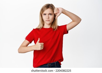 Portrait Of Child, Teen Little Girl Showing Thumbs Up And Thumbs Down, Decision And Weighing Concept, Like Or Dislike, Making Choice, Standing Over White Background.