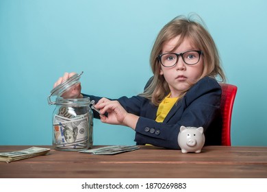 Portrait Of Child Who Steals Money From Parent Savings. Adorable Young Girl Wants To Be Rich. Kid In Glasses Can Count Money