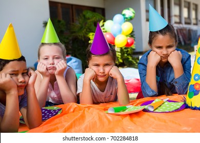 Portrait of children with hand on chin sitting at table during birthday party in yard - Powered by Shutterstock