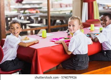 Portrait Of Children Having Lunch During Break Time In School Cafeteria