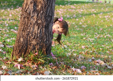 Portrait children, Little asian girl in pink qipao was smiling and playing hide-and-seek in the park