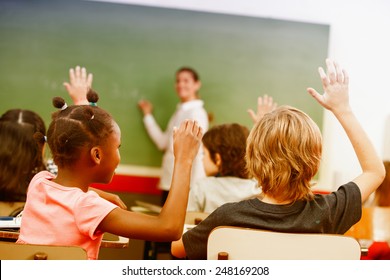 Portrait Of Children Raised Their Hands In A Multi Ethnic Classroom.