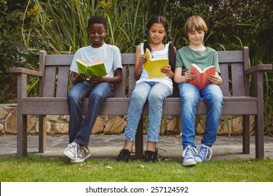 Portrait Of Children Reading Books At The Park