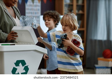 Portrait of children sorting plastic and paper in recycling class at preschool, copy space - Powered by Shutterstock