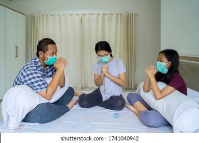 Portrait Of Christian Family Praying At Home Together While Wearing Face Mask And Stay Safe From Coronavirus 