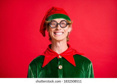 Portrait Of Christmas Fairy Funky Elf Guy In Geek Style Specs Toothy Smiling In Camera Isolated On Red Color Background