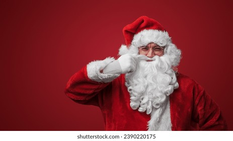 Portrait of christmas santa claus with glasses stroking his moustache looking at camera. - Powered by Shutterstock